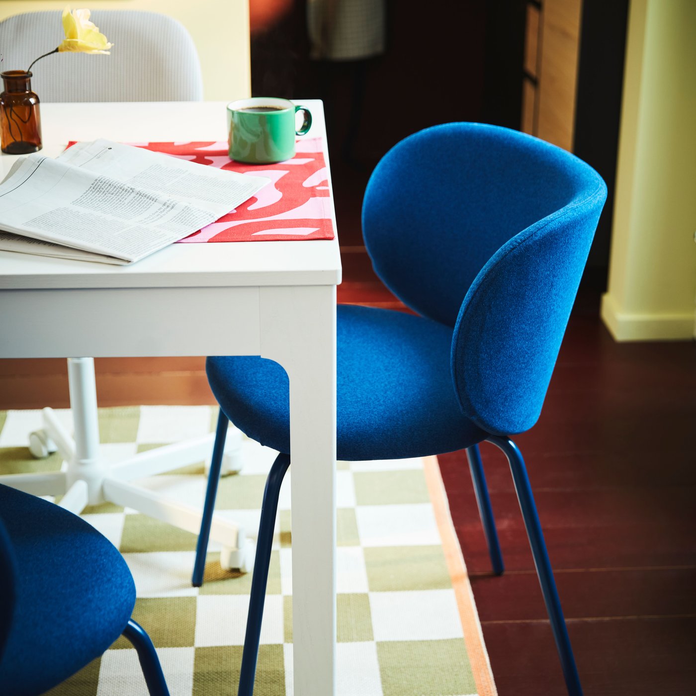 A KYRLBO chair in Tonerud blue by an EKEDALEN extendable table in white and on a KLASSRUM flatwoven rug in white and green.