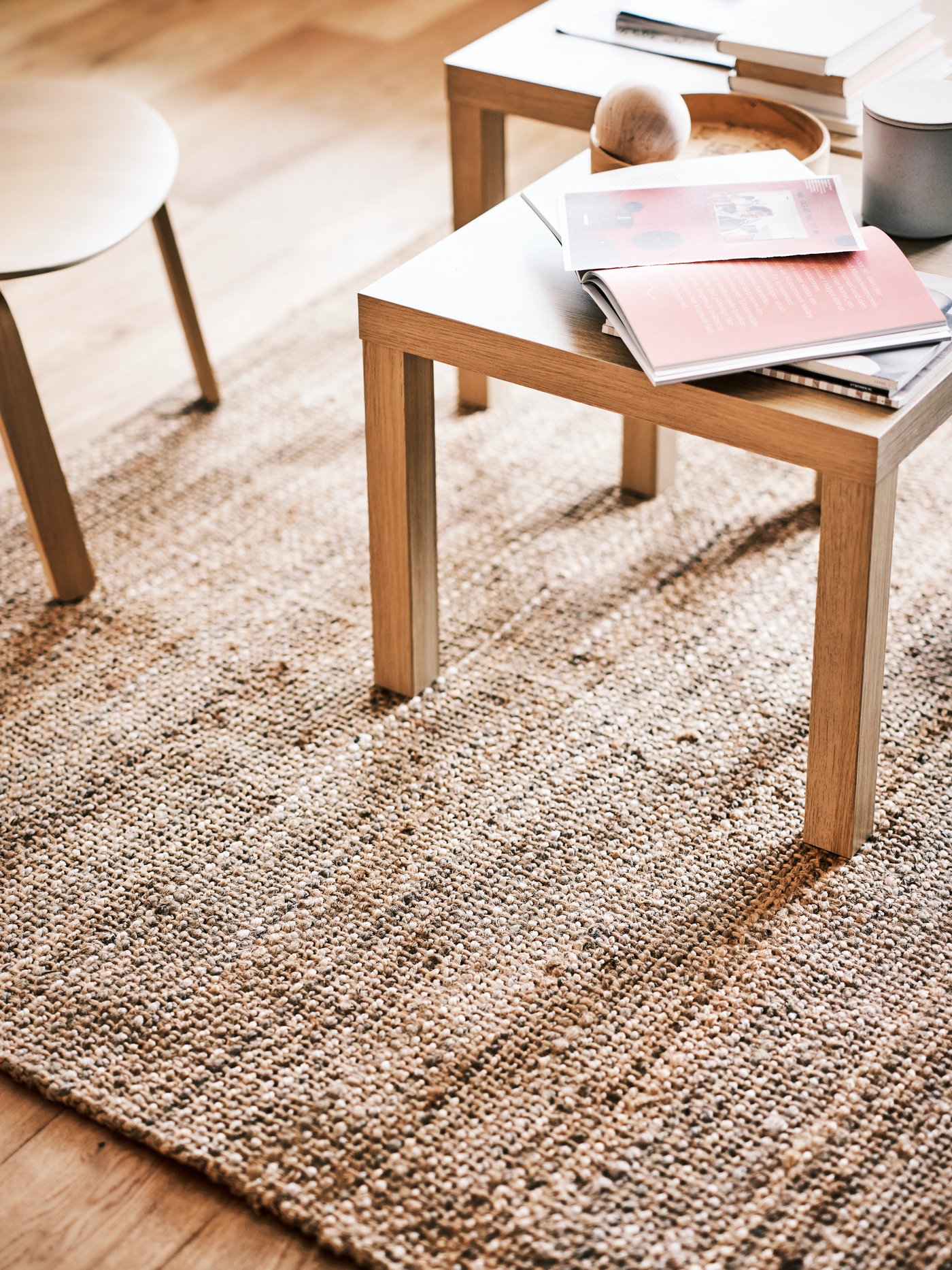 Área de un salón con una mesa auxiliar LACK, sobre la que descansan un tarro gris y blocs de notas, junto a un sillón FRÖSET, todo ello sobre una alfombra STRÖG.