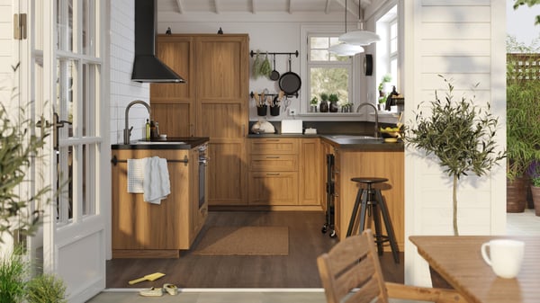 A sunny, white traditional-style kitchen with ENKÖPING brown walnut effect fronts and black mineral effect worktops.