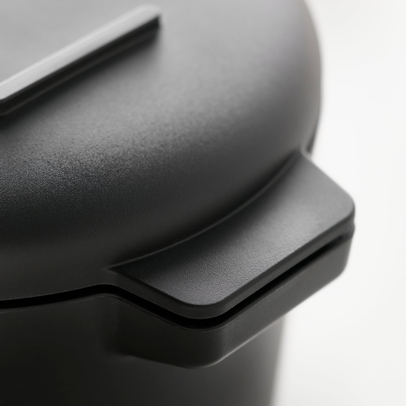 A close-up of a black TILLREDA multicooker featuring a secure handle and smooth lid.