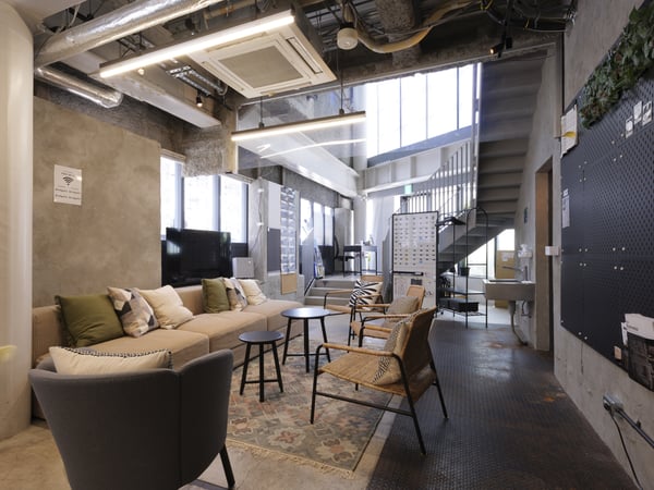 階段付きのラウンジスペース。多様な椅子とテーブルが配置され、自然光が広がる開放的な空間