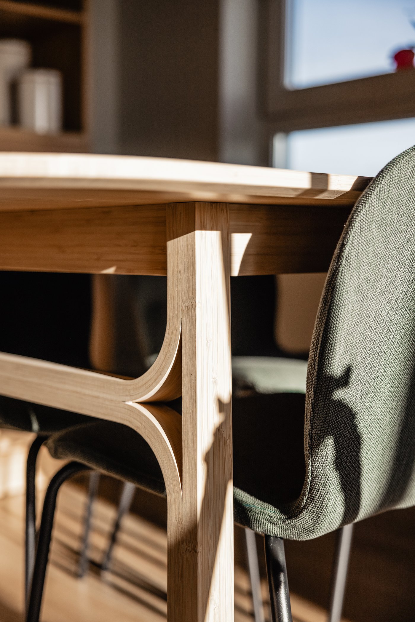 Close-up van een VOXLÖV eettafel in licht bamboe met daaromheen 4 grijsgroene SKÅLSTA eettafelstoelen.
