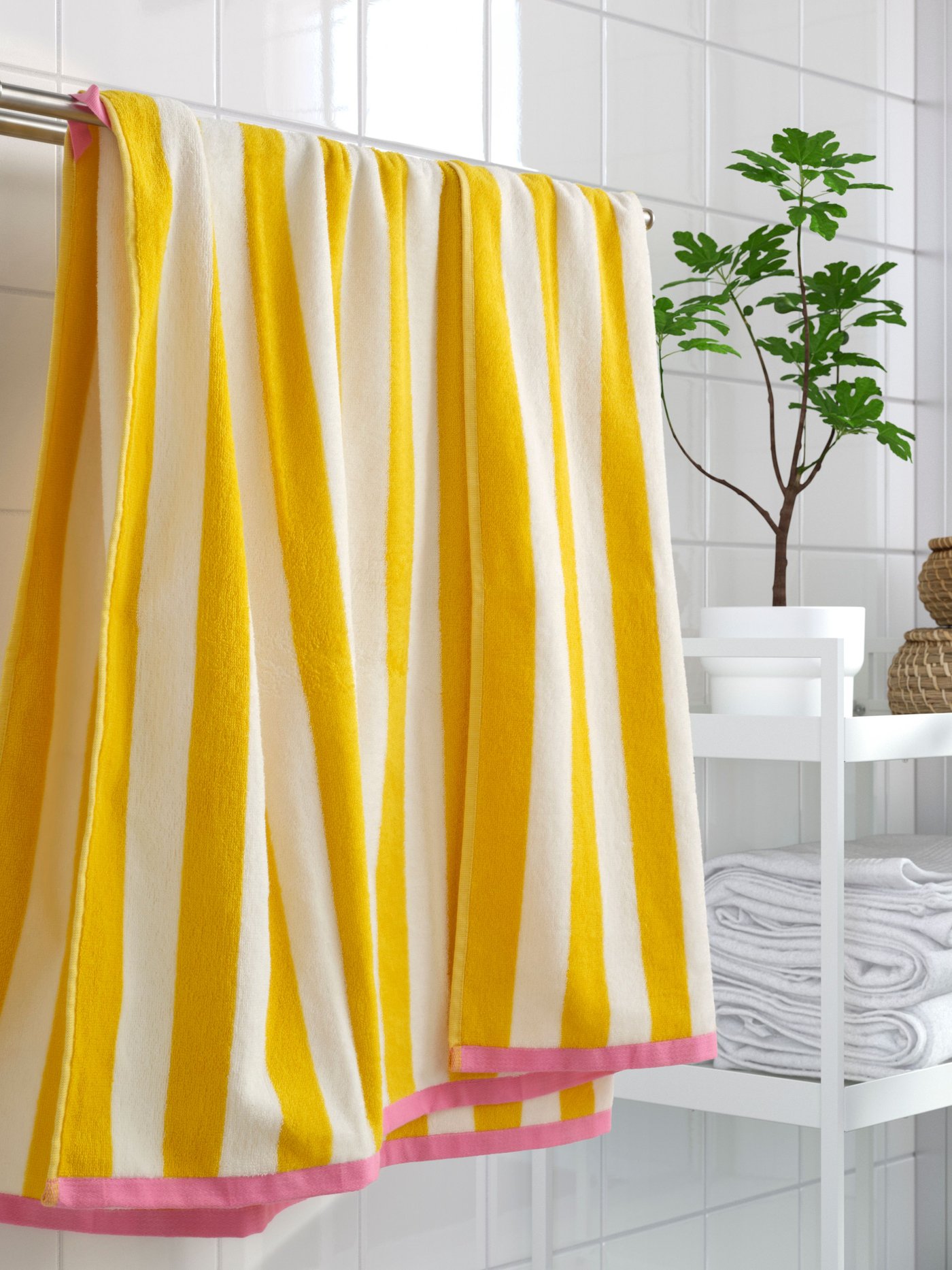 En randig gulvit handduk hänger på en vit badrumshylla.