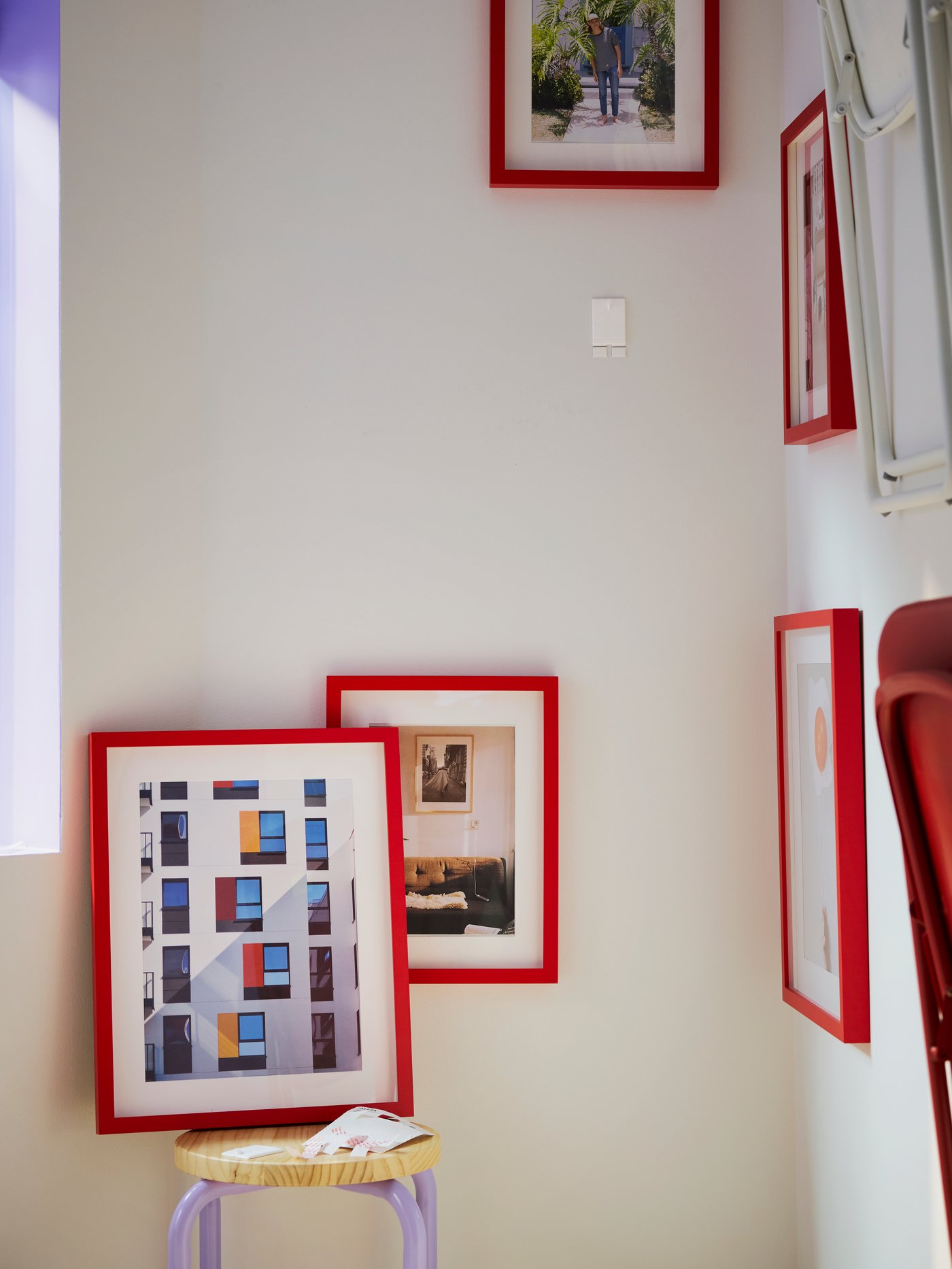A corner of a room with a lot of red picture frames being hung up with the help of ALFTA adhesive hooks.