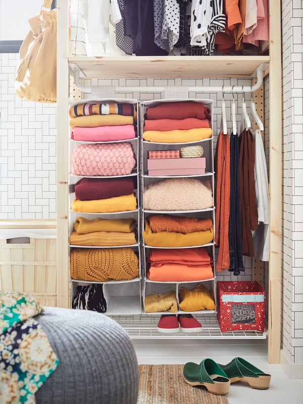 An open IVAR unit used as a wardrobe, including a rail. Clothes and shoes can be seen on different levels.