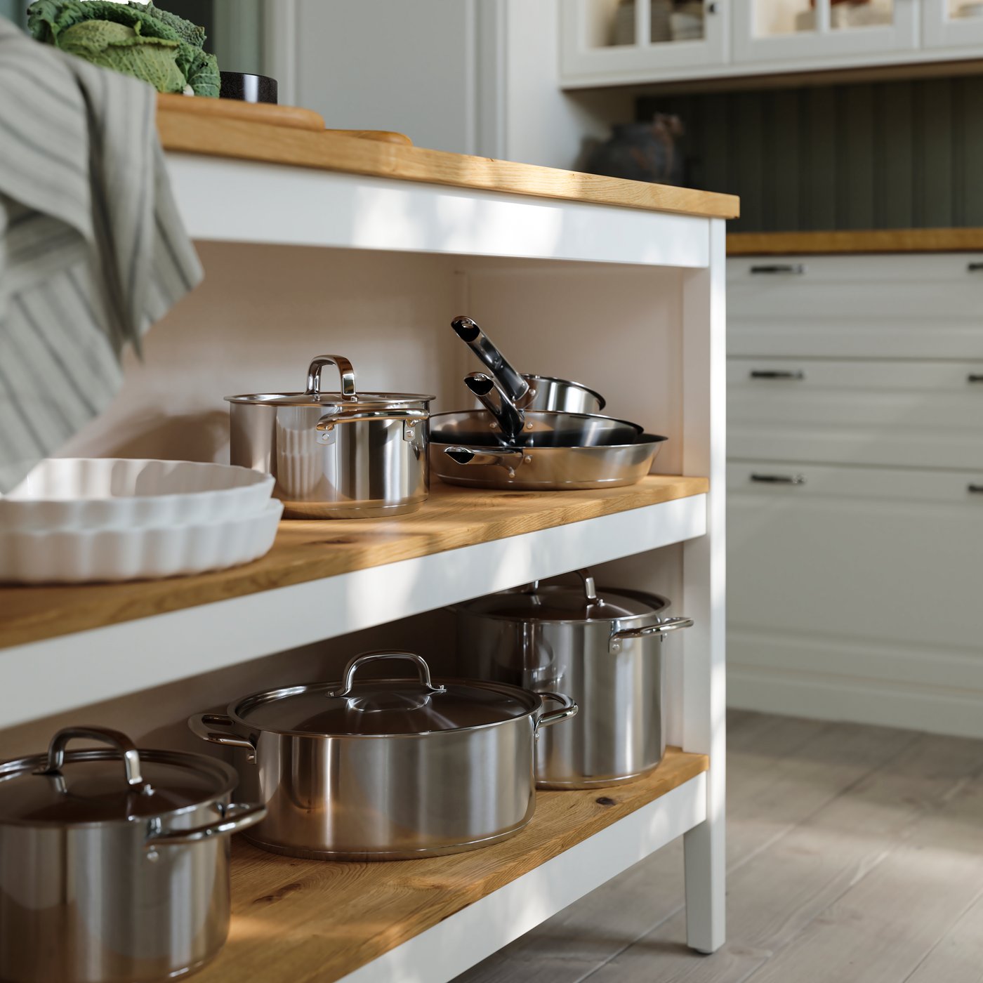 Stainless steel IKEA 365+ cookware on the shelves of an off-white/oak TORNVIKEN kitchen island.