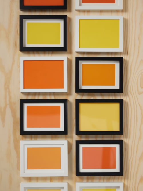 Living room close-up of multiple black RÖDALM frames placed on a well next to multiple white RÖDALM frames.