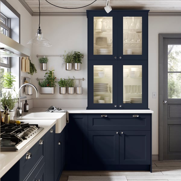 A black kitchen with silver handles and a light worktop.