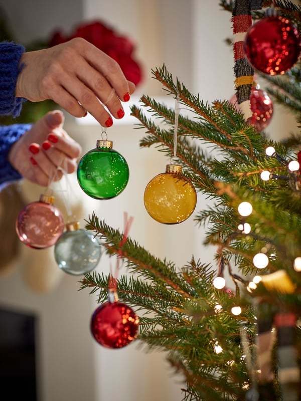 Una persona decorando un árbil de Navidad con decoraciones VINTERFINT.
