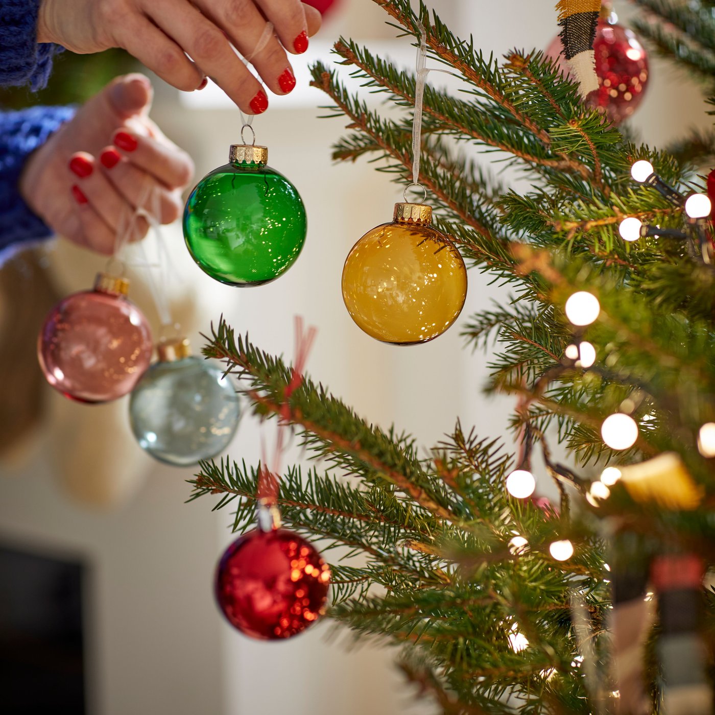 Una persona sacando adornos de un árbol de navidad.