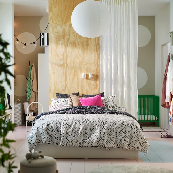 A VIHALS bed with 4 storage boxes covered in black and white BJÖRKGRÅMAL bed linen with a white curtain behind it.