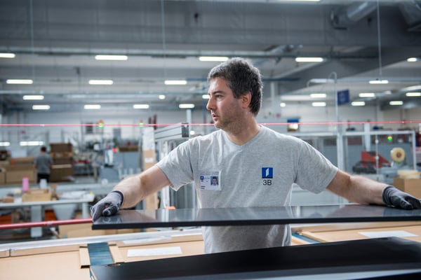 A male employee is lifting a black wooden board in a production environment.