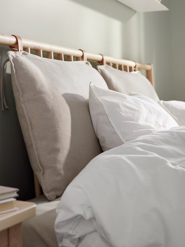 A close up of  a headboard with pillows and ÄNGSLILJA bedding.