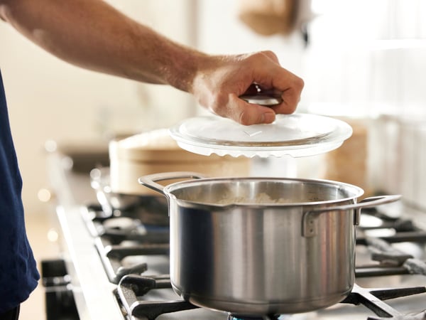 Una persona despando una olla HEMKOMST sobre una cocina.