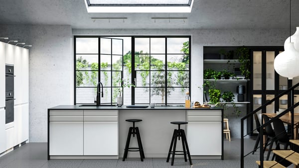 Big modern island in an extension room with big double glass doors. The doors are high-gloss white and the worktop is marble black, with sink and a small breakfast bar. 