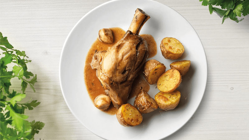 Geschmorte Lammhaxe mit Rosmarinkartoffel auf einem Teller präsentiert.