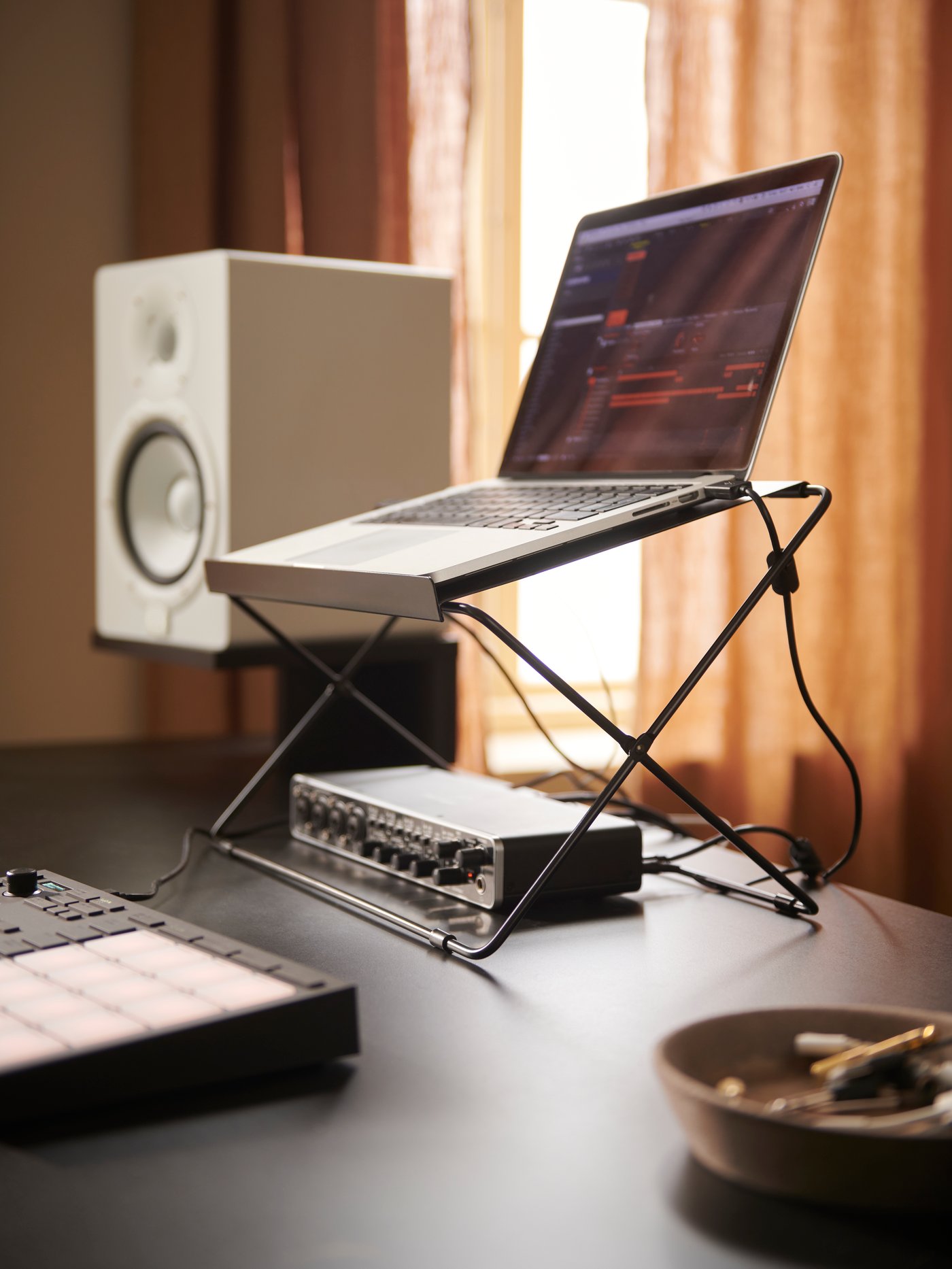 A black OBEGRÄNSAD armchair, rug and cushion cover on wooden floorboards next to an electric guitar and white curtains.