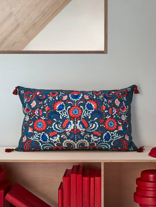 Focalizarea camerei de zi pe o pernă pătrată colorată cu broderie tradițională scandinavă, plină cu pene de rață.