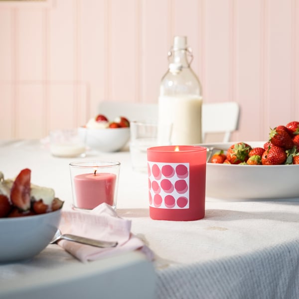 Bougie parfumée dans un verre BLODBOK fraise/rose vif sur une table de salle à manger.