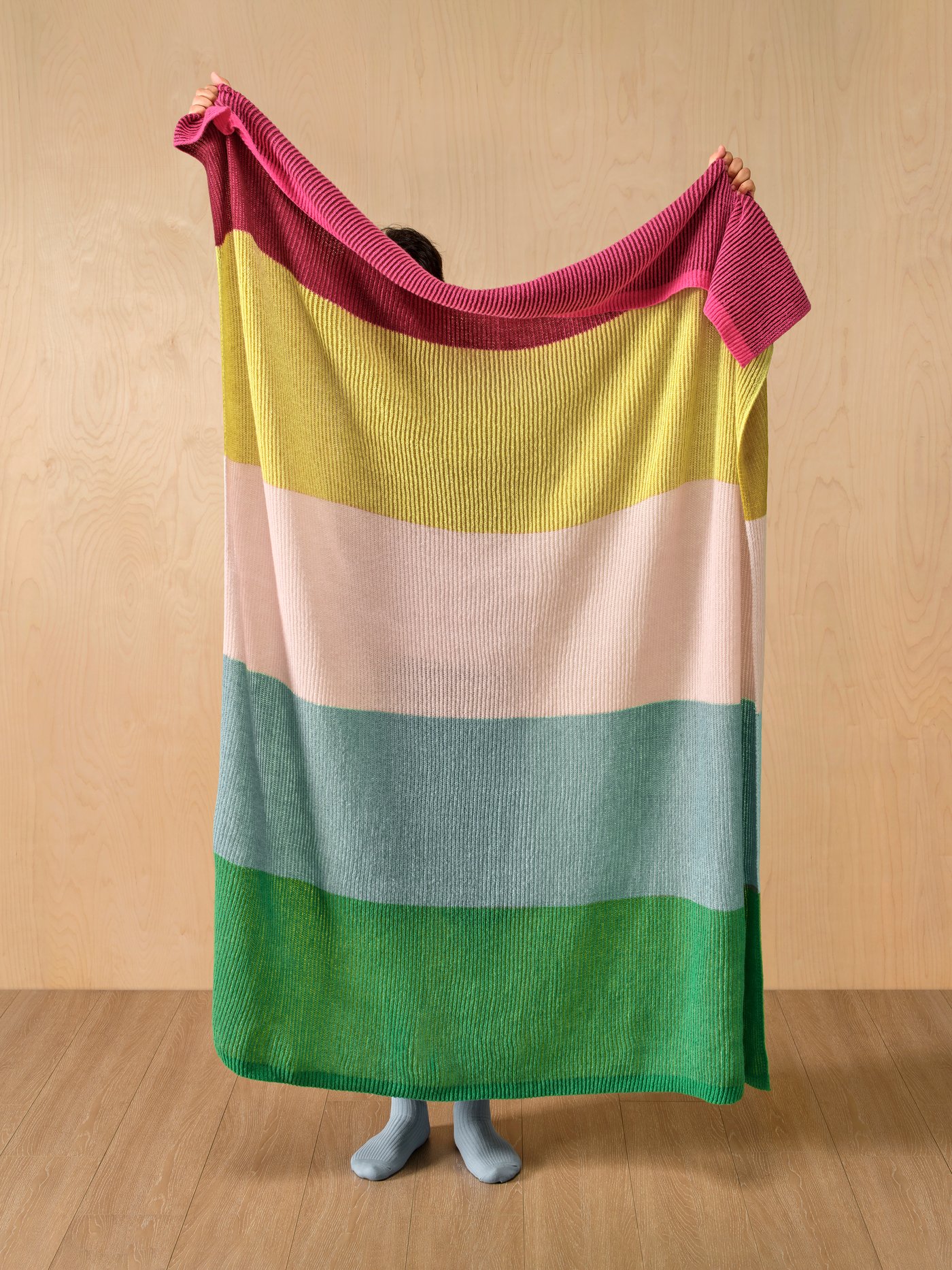 Cobija MARGOSATRÄD multicolor sostenida por una persona. 