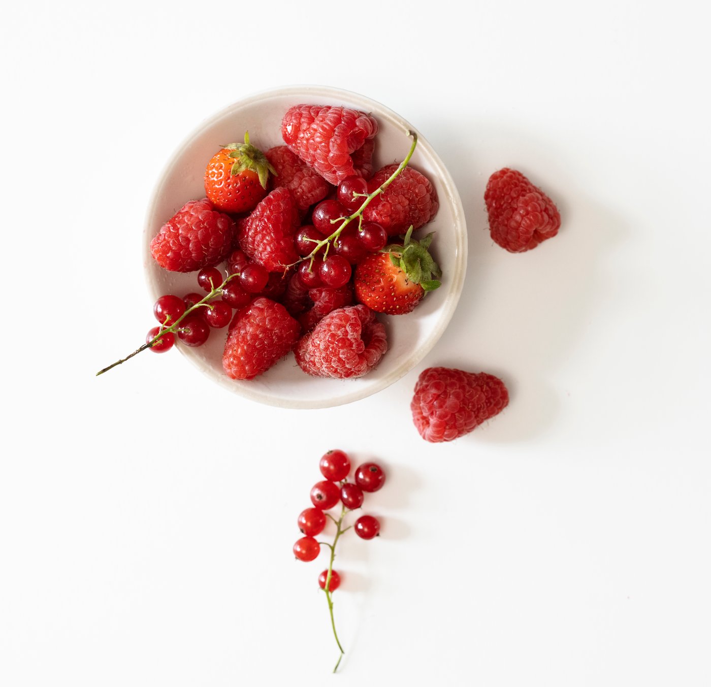 Schüssel mit Erdbeeren, Himbeeren und roten Beeren auf weißem Hintergrund