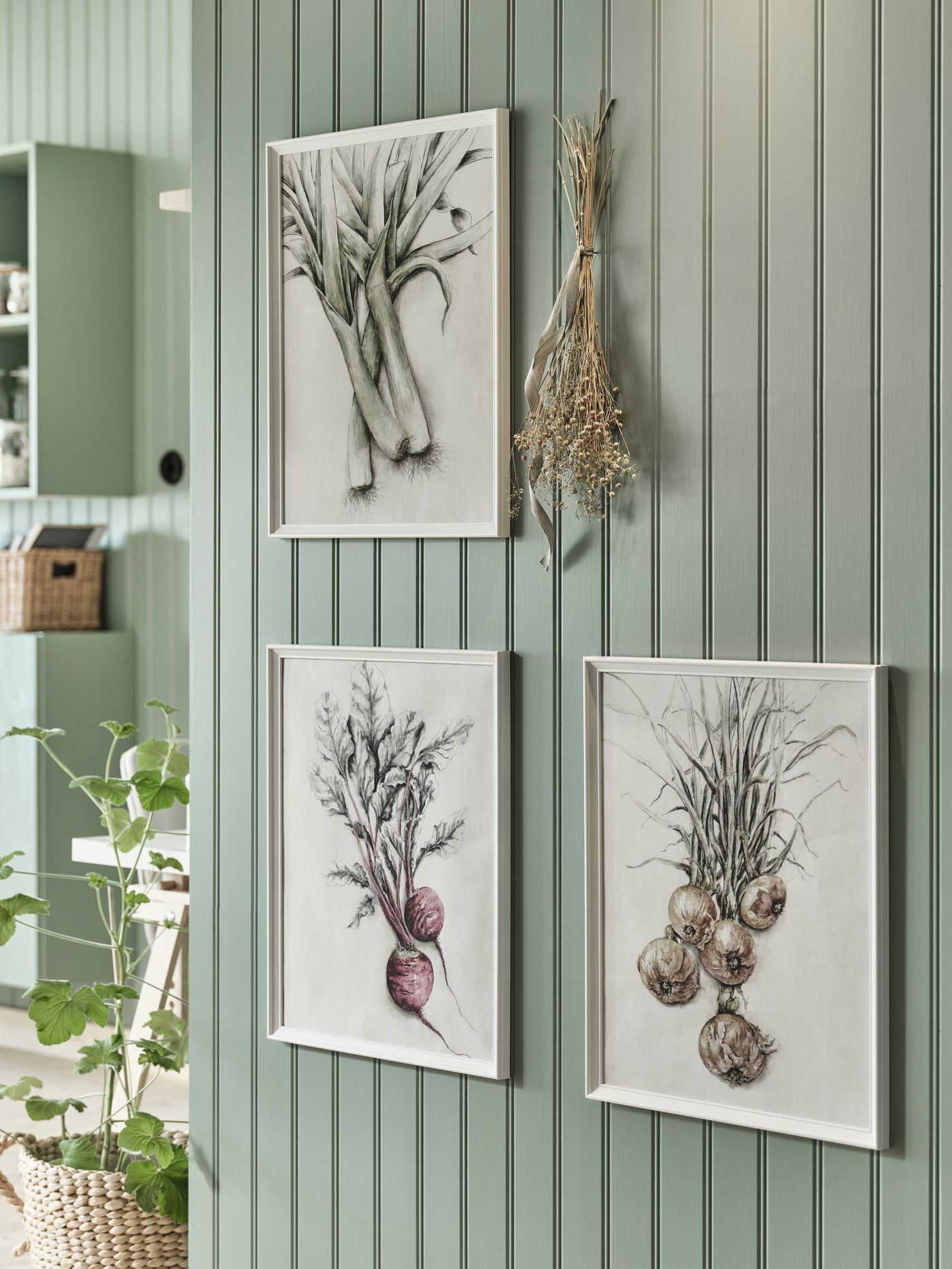 Gruppe af indrammede prints i landlig stil på en malet væg af træpaneler.