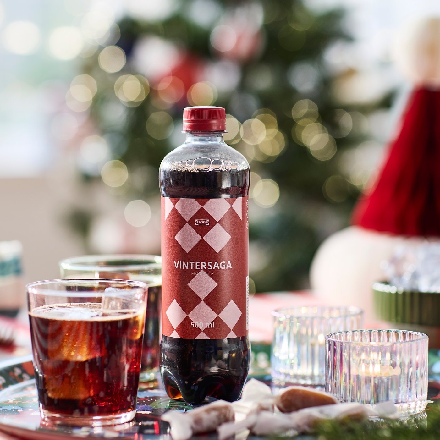 A bottle of VINTERSAGA festive drink beside two glasses filled with the drink and ice cubes.