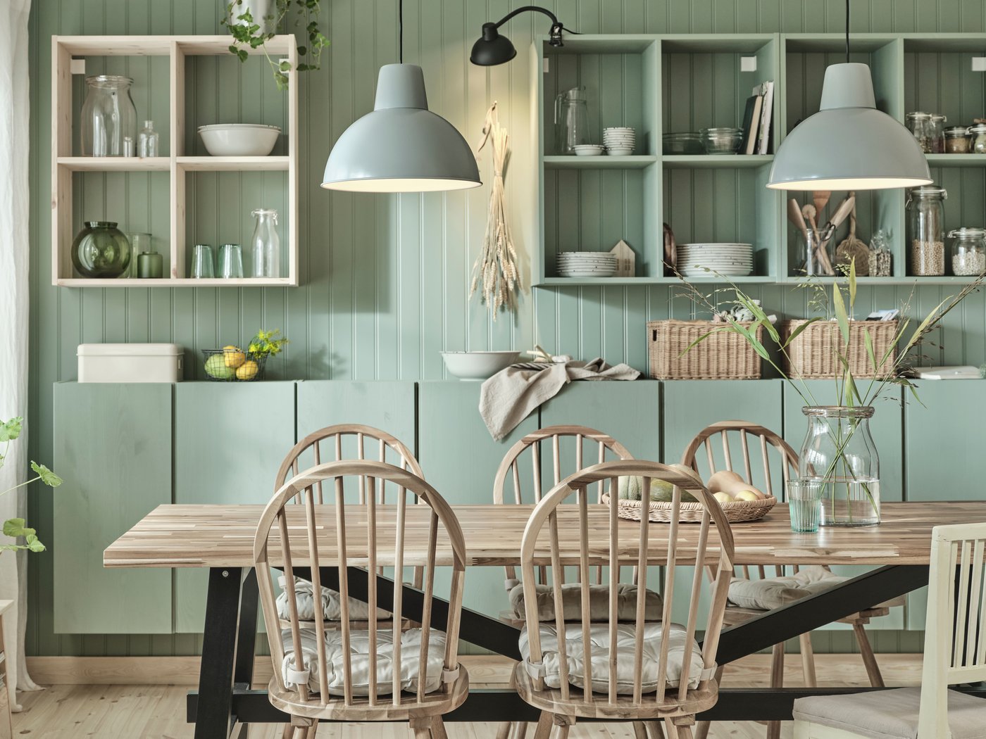 Et stort SKOGSTA spisebord i træ med fire matchende stole og en hvid børnestol samt en glasvase med blomster.