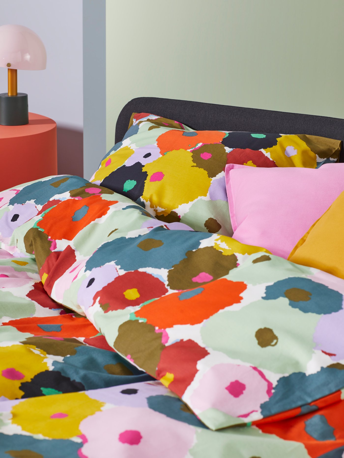 Una cama SLATTUM vestida con una funda nórdica MURREVA de flores y fundas de almohada MURREVA de flores.