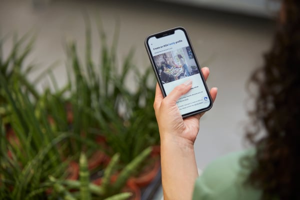 En hånd holder en mobil over nogle planter og er ved at logge ind på sin IKEA Family profil.