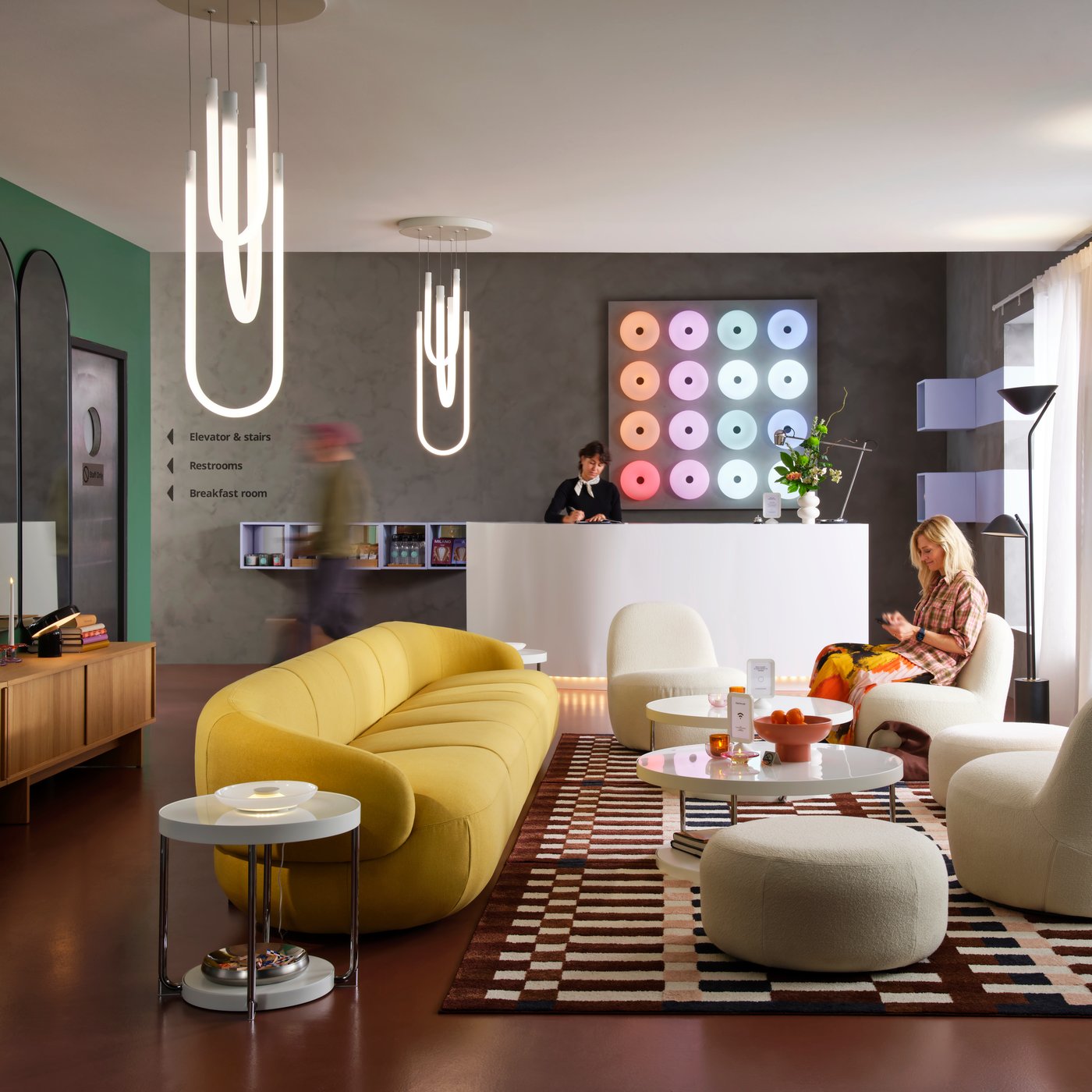 GUL LILLESÄTER soffa tillsammans med vita fåtöljer i loungeyta med brunt golv och gråa väggar,