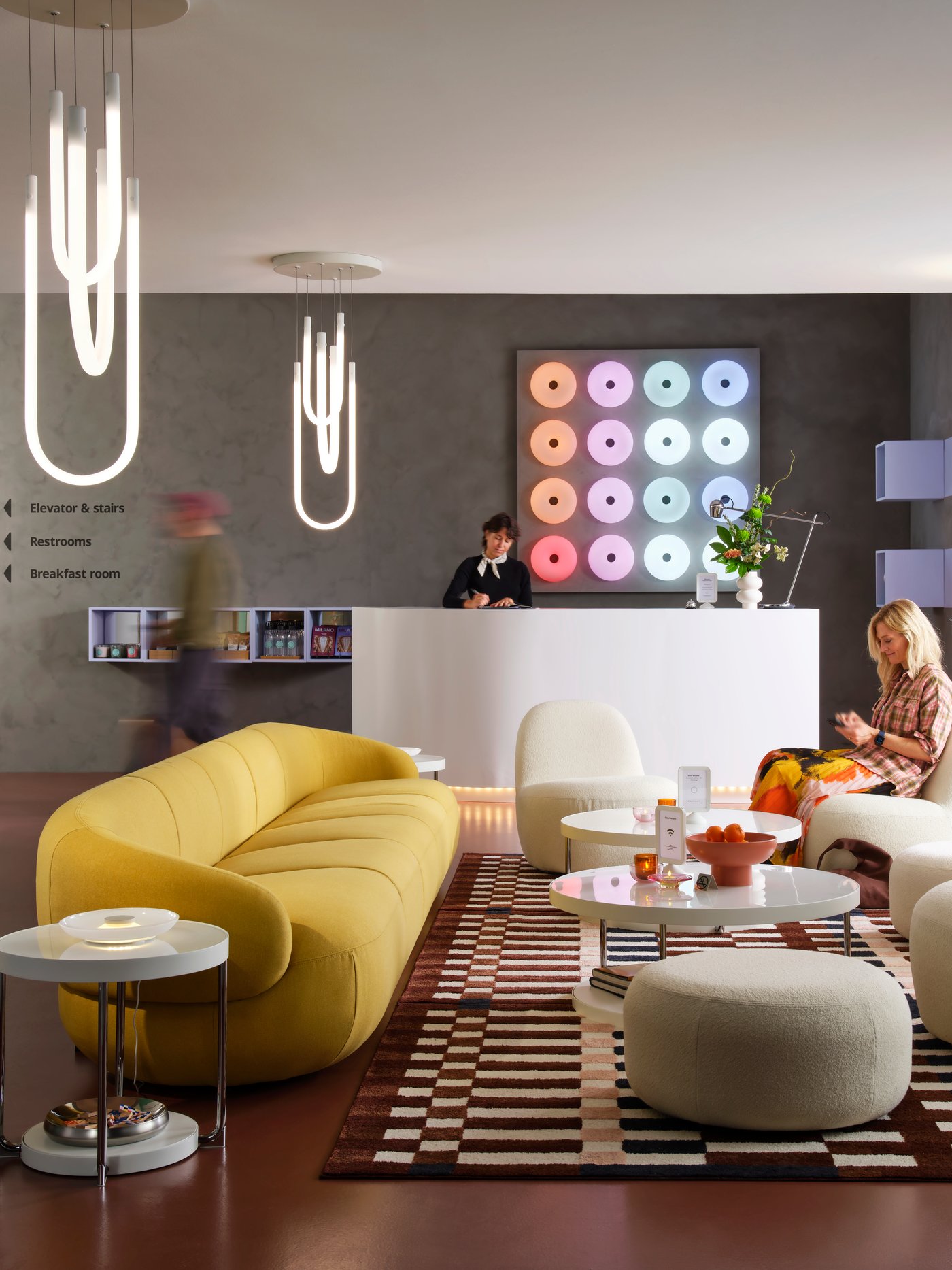 Een LILLESÄTER 6-zits bank in Gunnared heldergroen/geel in de lobby van een modern hotel met verschillende mensen in de ruimte.