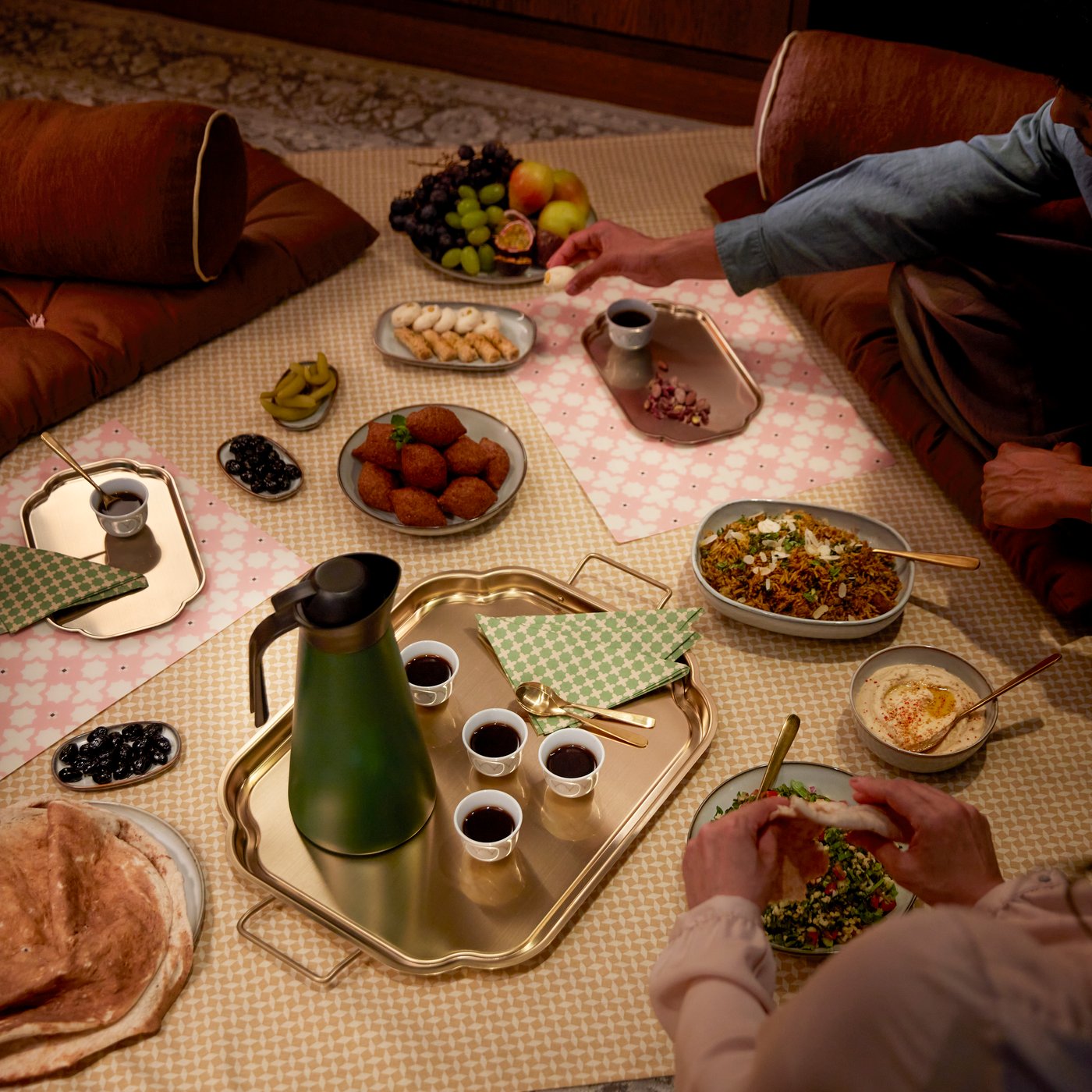A gold-coloured GOKVÄLLÅ serving tray holds various items on a patterned cloth in a cosy setting.