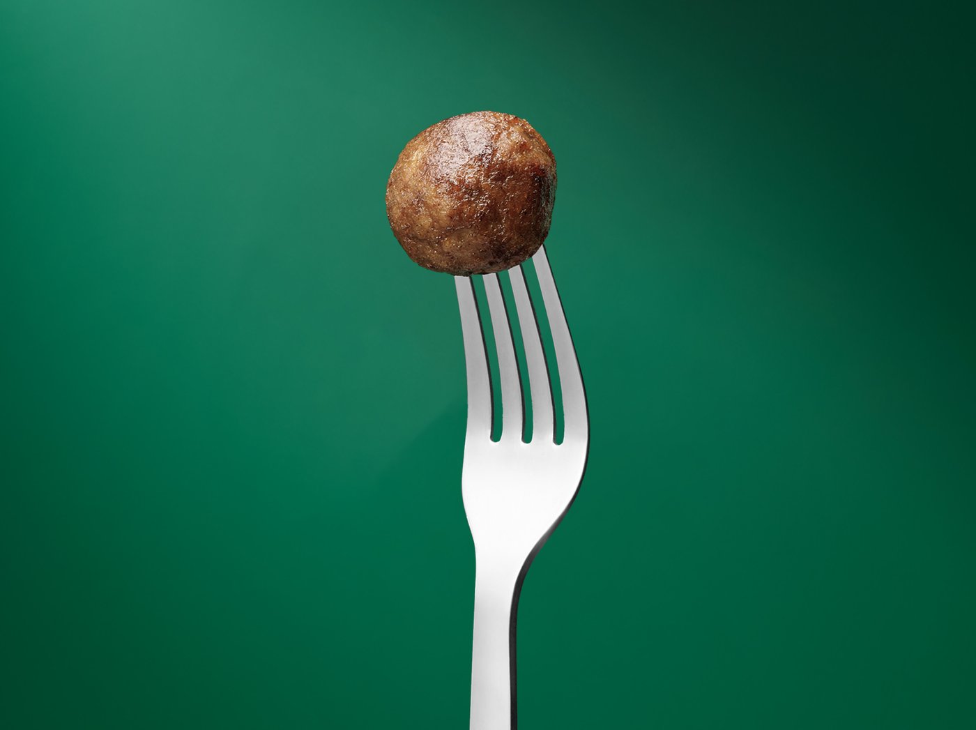 Vihreää taustaa vasten haarukka, jossa lihaton pyörykkä.
