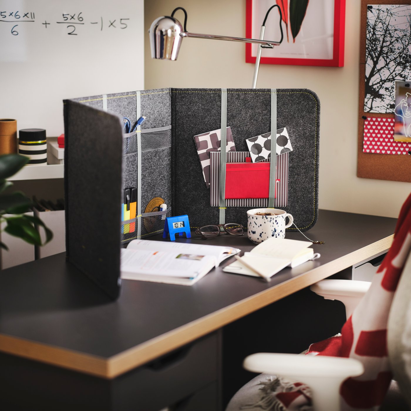 Es ist eine graue ÖVNING Schreibtischtrennwand mit Fächern auf einer dunkelgrauen LAGKAPTEN Tischplatte in Holzeffekt zu sehen.