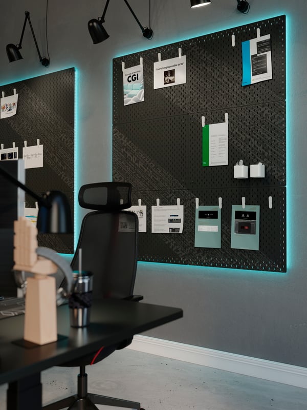 On a wall by a workspace with a MATCHSPEL gaming chair are large neon-backlit noticeboards formed by black UPPSPEL pegboards.
