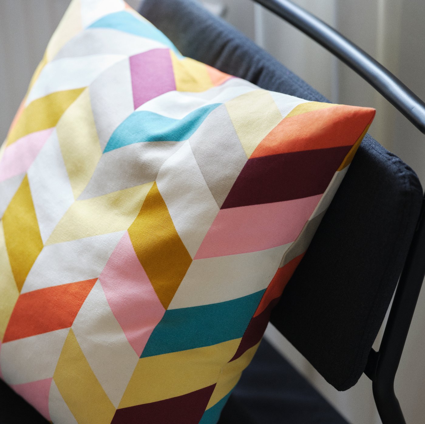 A multicolour HANNELISE cushion on a dark grey LINNEBÄCK easy chair.