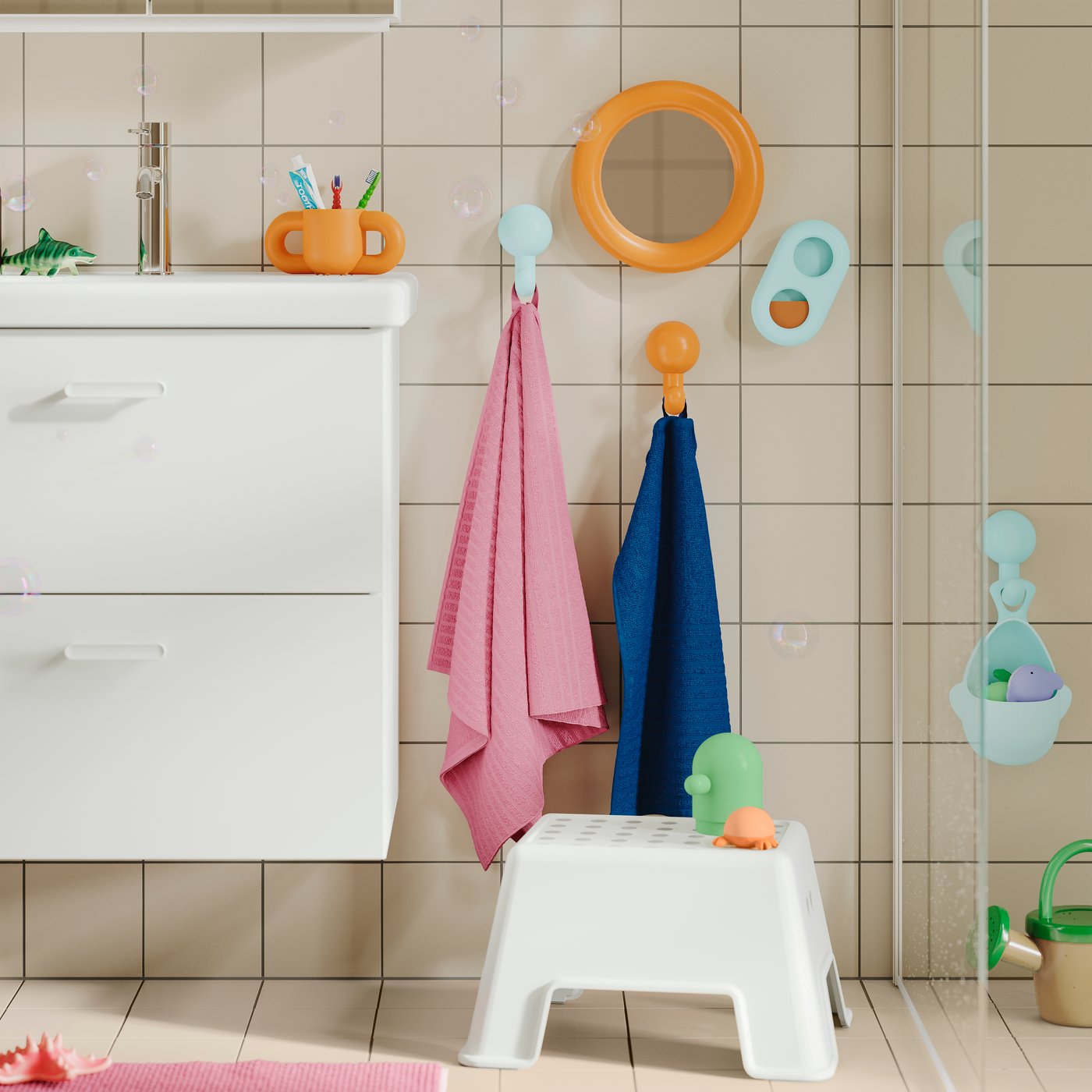 A BOLMEN step stool on the floor, a sink and colourful towels and accessories on the wall in child-friendly height.