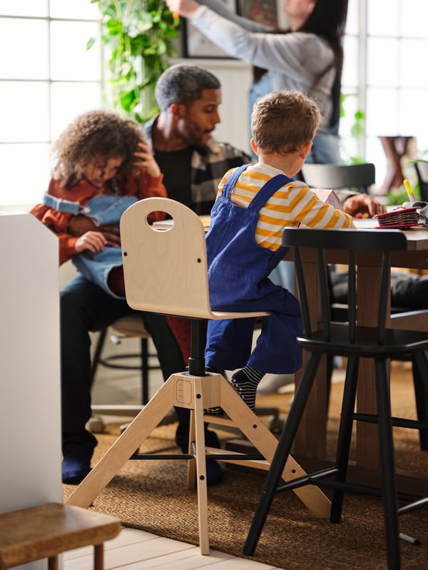 Child on a child's chair surrounded by family