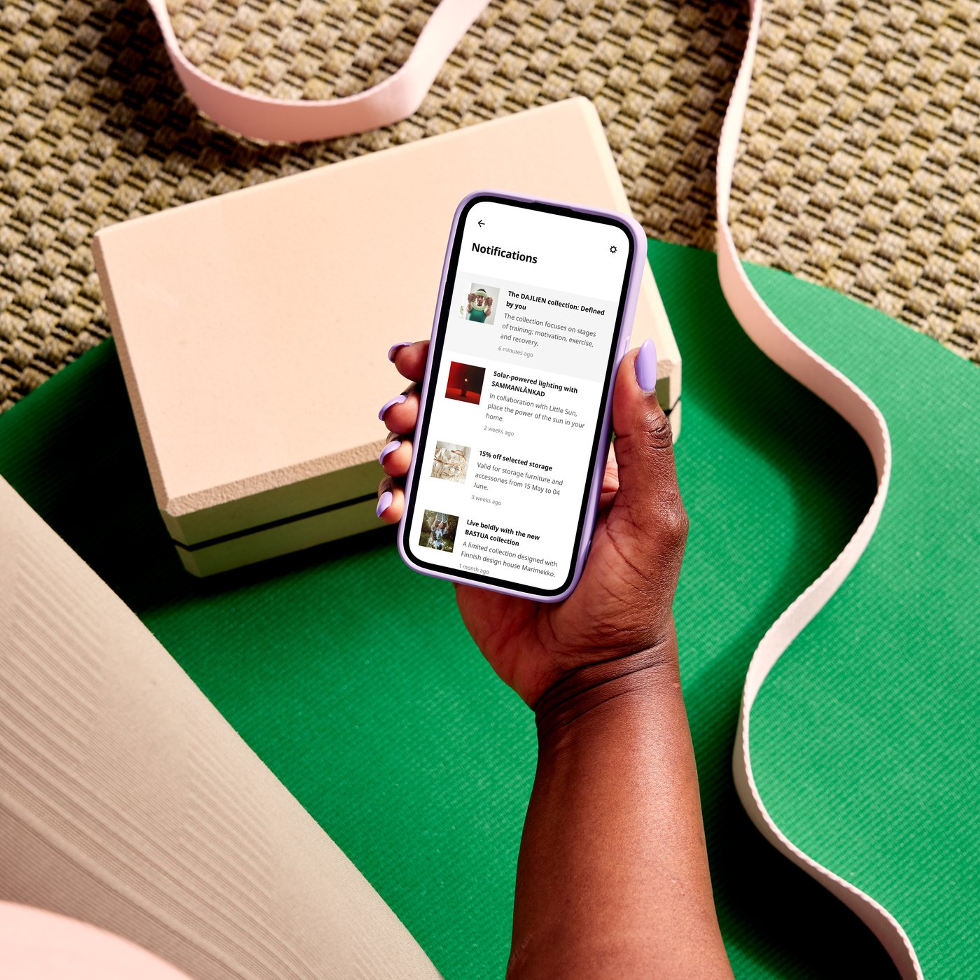 A person holding a smartphone showing notifications on the screen, sitting on a green yoga mat.