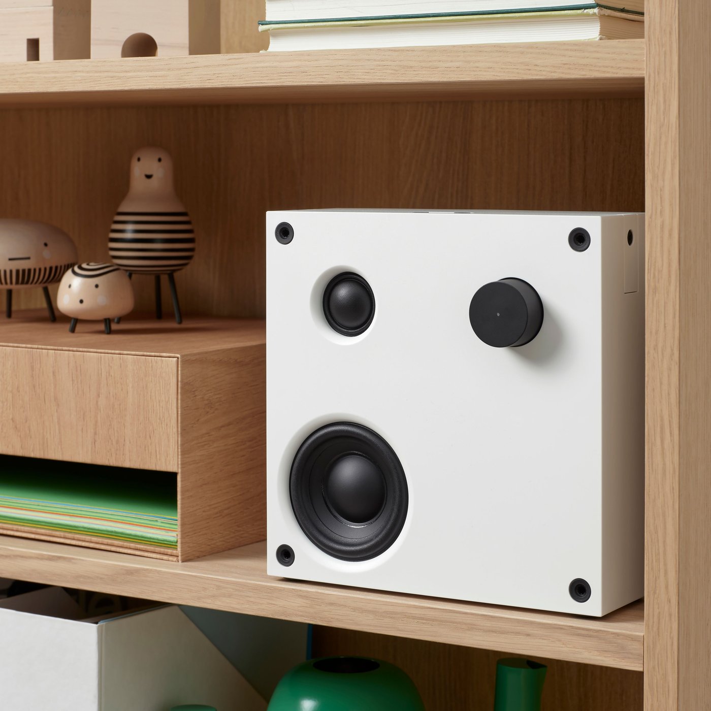 A white VAPPEBY Bluetooth speaker stands on a shelf next to some wooden DVÄRGTALL decoration figures.