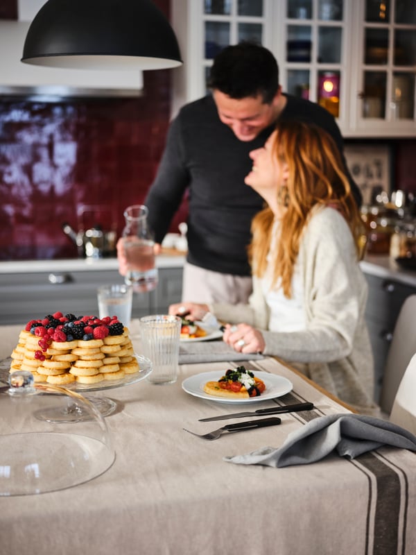 A couple celebrating with pancakes for breakfast in the kitchen.