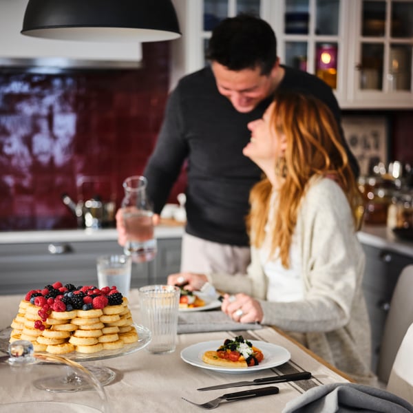 A couple celebrating with pancakes for breakfast in the kitchen.