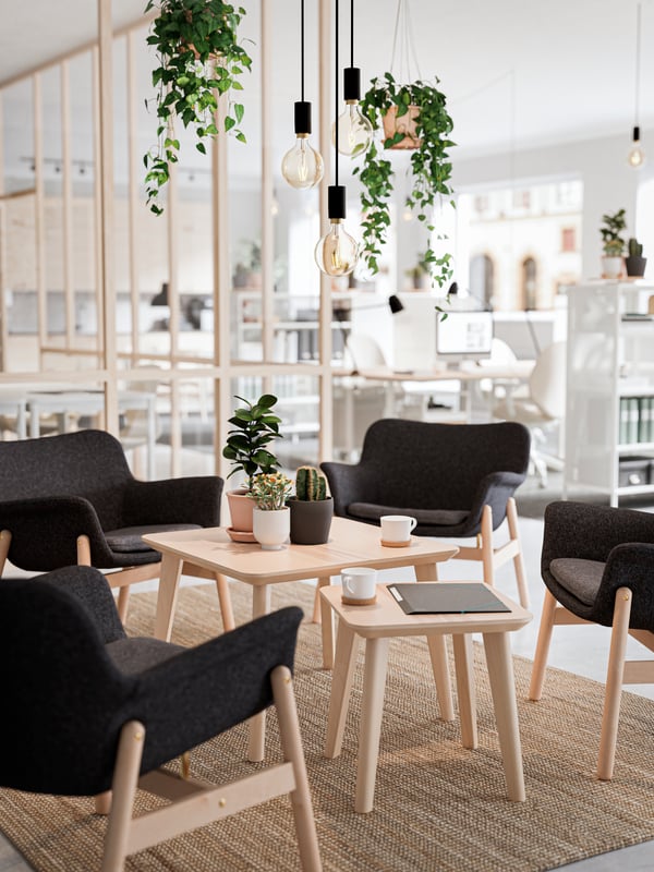 A sitting area in an office with light wood furniture and black modern chairs.