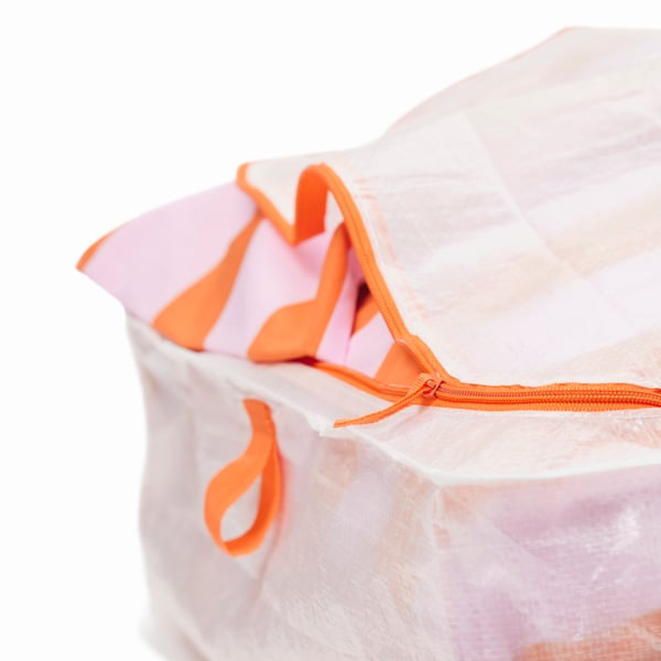 Detail rohu úložného dílu PÄRKLA. Oranžový zip je částečně rozepnutý a odhaluje pruhovaný textil uvnitř.