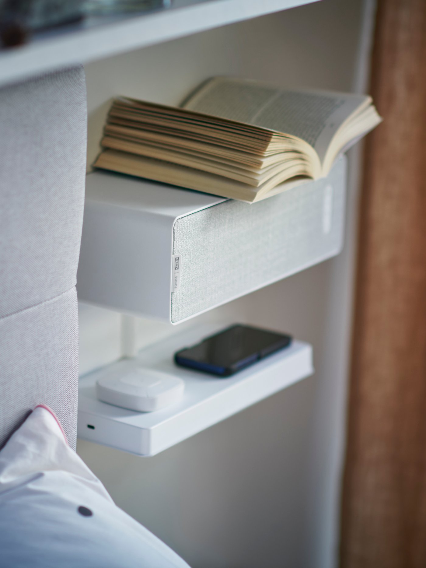 Une enceinte SYMPHONIC blanche et une tablette SYMPHONIC avec chargeur sans fil.