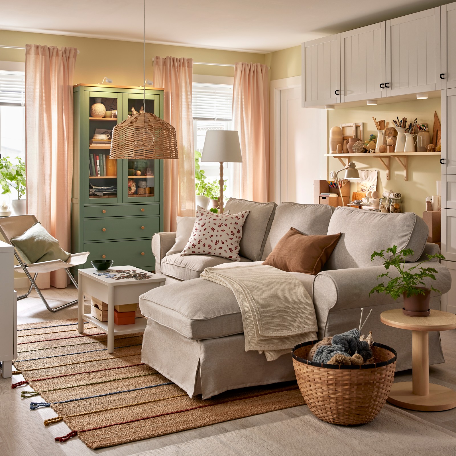 An EKTORP sofa with chaise longue stands in a functional living room near a HEMNES glass-door cabinet and some BESTÅ storage.