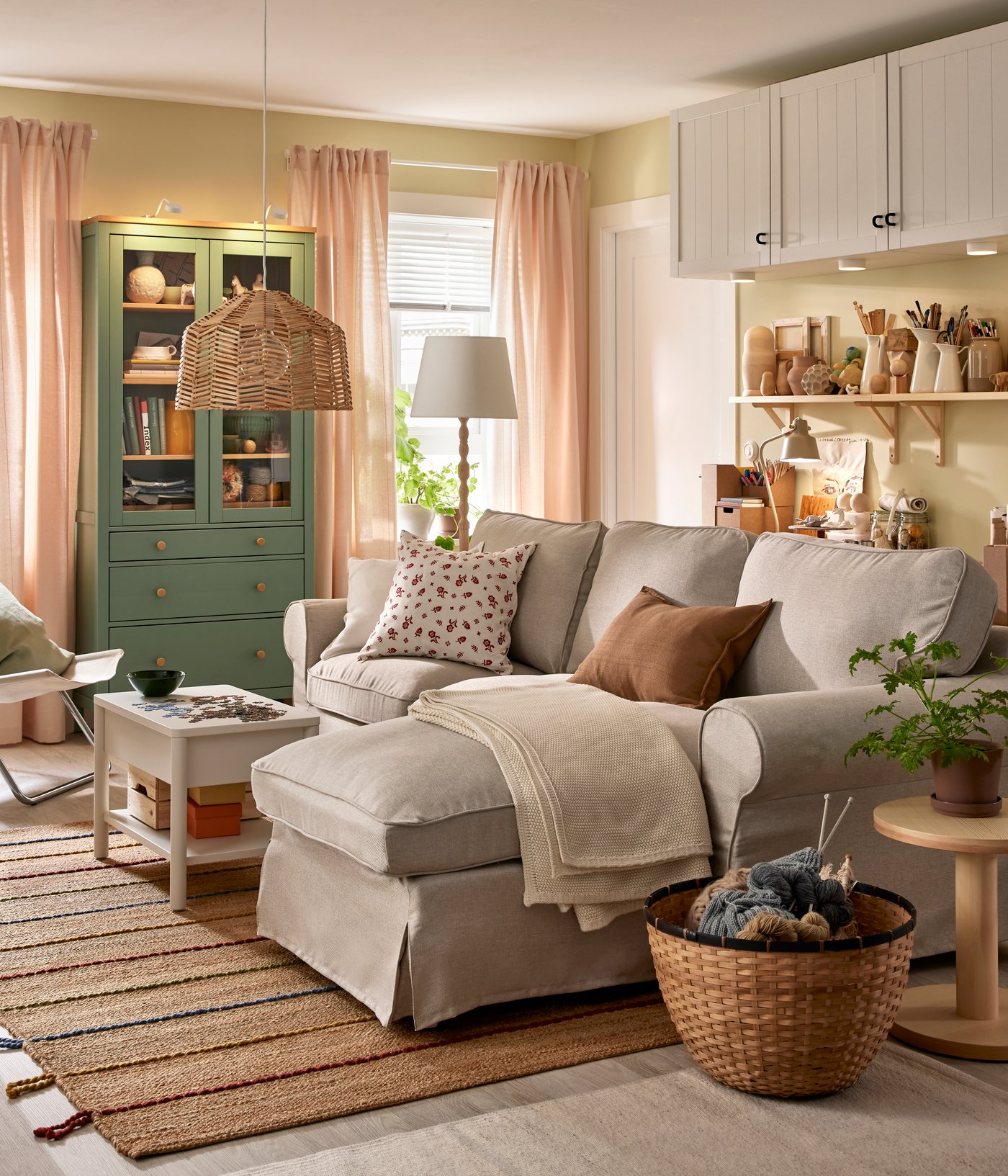An EKTORP sofa with chaise longue stands in a functional living room near a HEMNES glass-door cabinet and some BESTÅ storage.