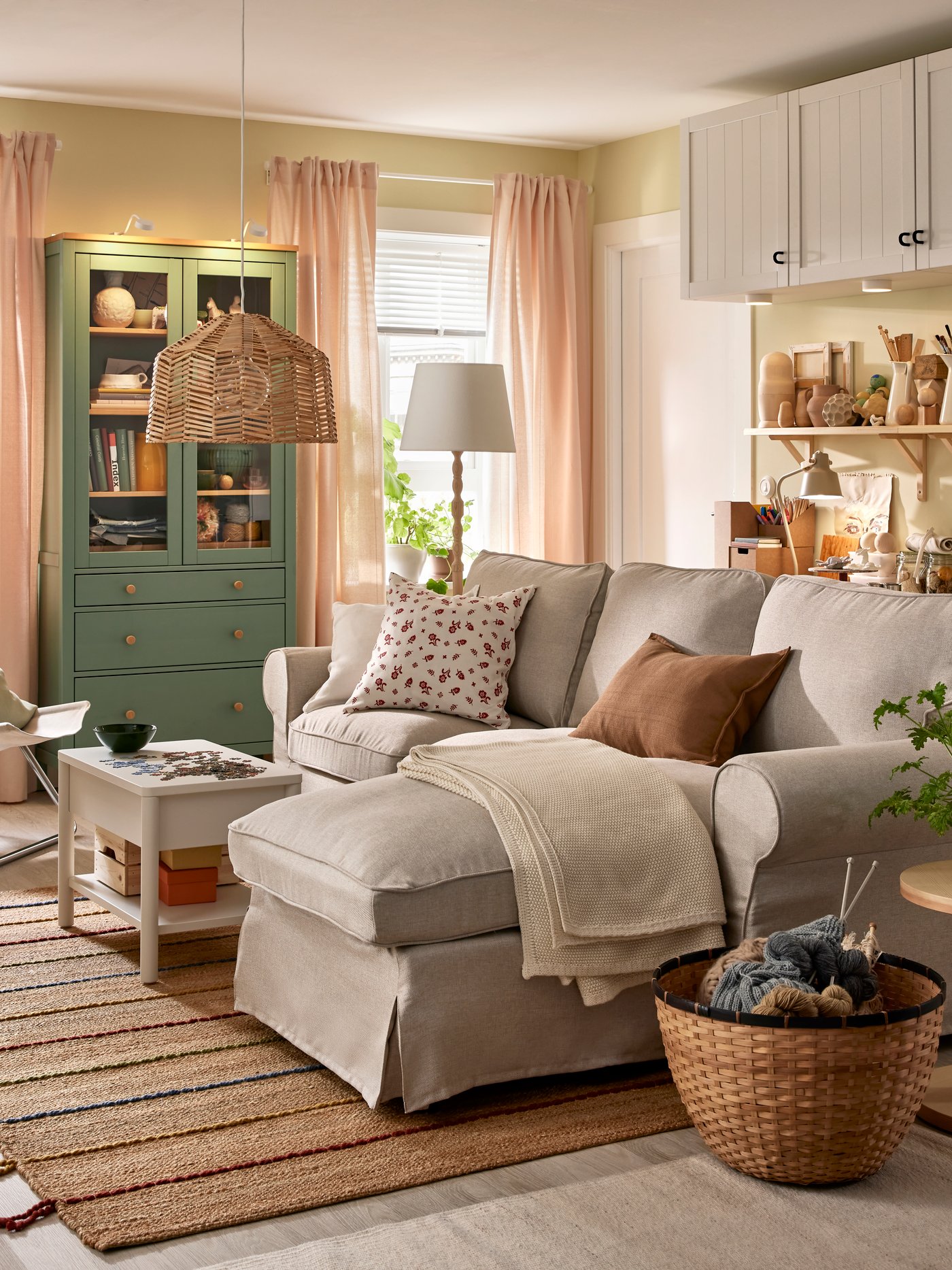 An EKTORP sofa with chaise longue stands in a functional living room near a HEMNES glass-door cabinet and some BESTÅ storage.