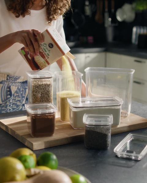 Een lange eettafel vol serviesgoed, omringd door verschillende stoelen die klaar staan om de gasten te ontvangen, met lampen die aan het plafond hangen.
